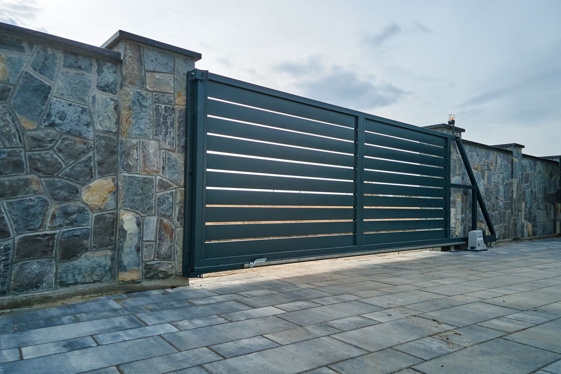 Large portail coulissant automatique avec télécommande installée dans un haut mur de fense en pierre. Concept de sécurité et de protection
